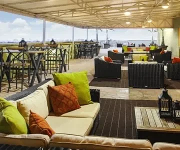 Outdoor restaurant patio with comfortable seating, canopy, and water view.