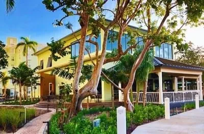 Modern two-story building with patio in lush tropical garden.