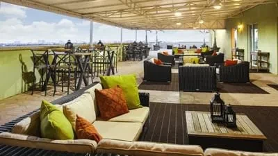 Spacious outdoor patio with varied seating, canopy, and hazy city view.