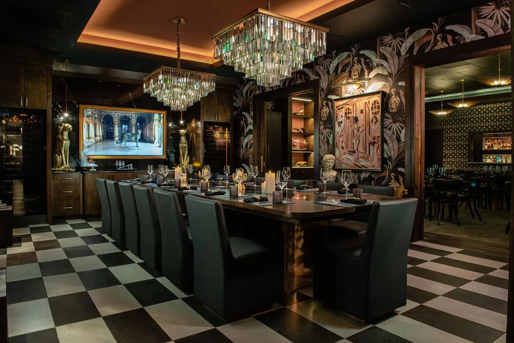 Luxurious private dining room with chandeliers, checkered floor, tropical wallpaper.