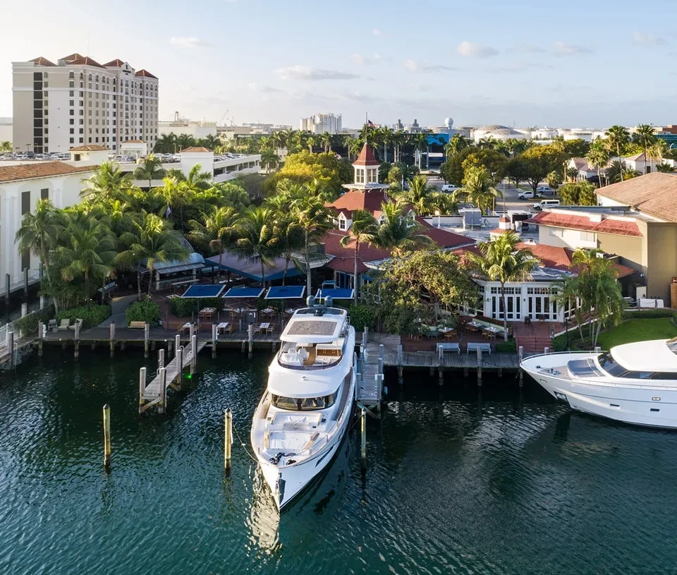 Aerial photo: red-roofed waterfront restaurant, yachts, and tropical marina.