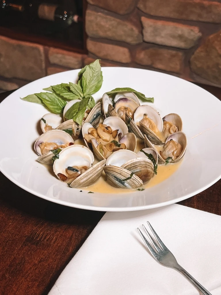 Steamed clams with basil, garlic, and creamy sauce in a bowl.