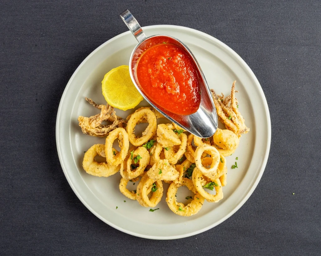 Golden fried calamari with marinara sauce and lemon wedge.