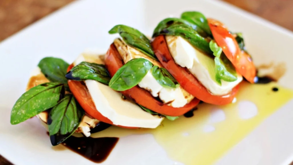 Plated Caprese salad with tomatoes, mozzarella, basil, balsamic, and olive oil.