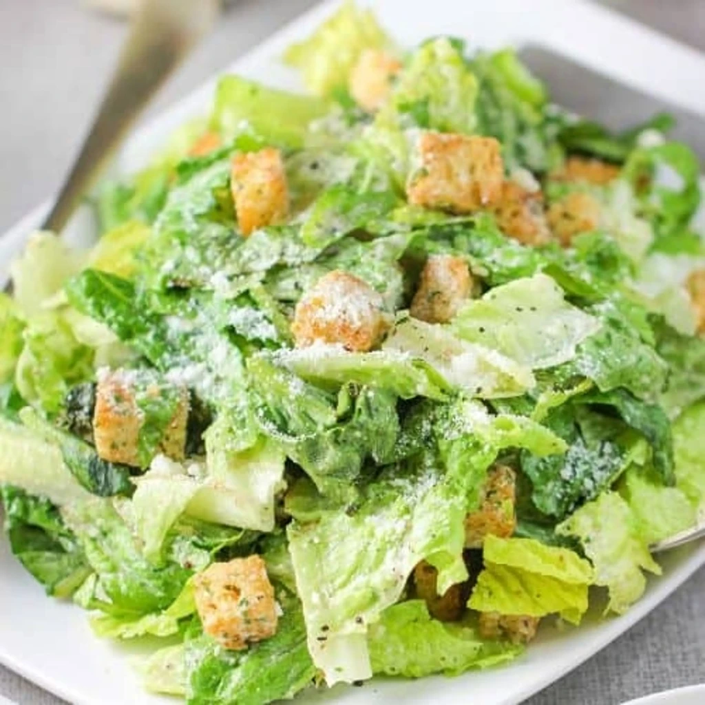 Top-down Caesar salad with romaine, creamy dressing, croutons, Parmesan.