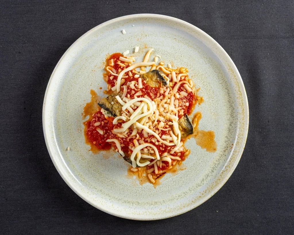 Close-up overhead of eggplant parmesan with tomato sauce and melted cheese.