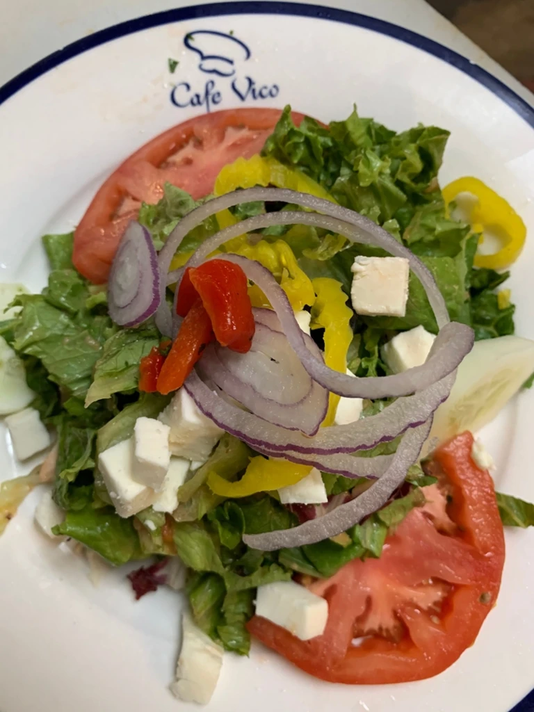 Close-up of fresh salad: lettuce, tomato, feta, onion, peppers.