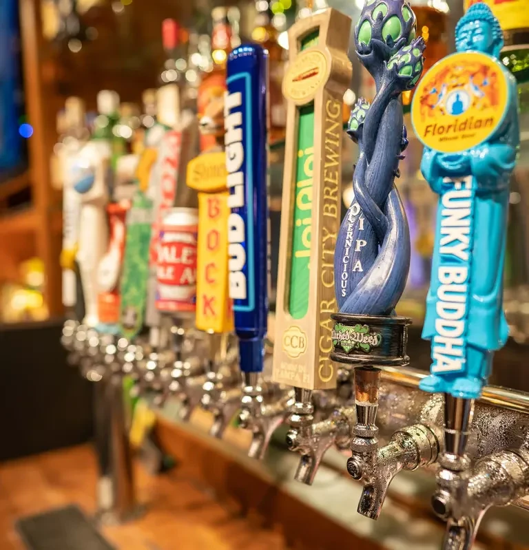 A close-up of various beer tap handles at a bar.