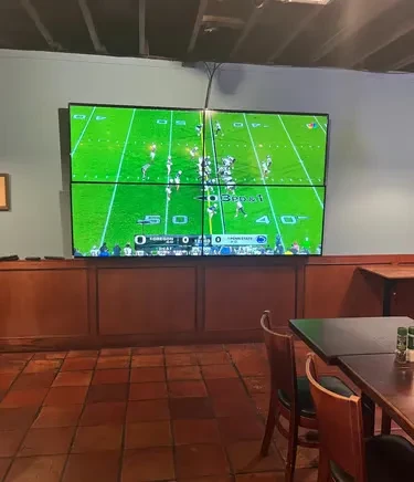 Sports bar interior: large video wall displays Oregon vs. Penn State football.