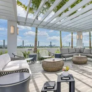 Spacious outdoor lounge patio with furniture, white pergola, city skyline.