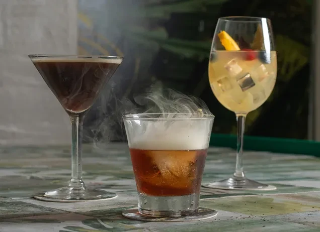 Three cocktails: martini, smoking rocks glass, and garnished wine glass.