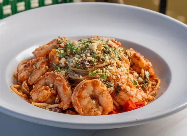 Close-up: spaghetti, shrimp, tomato sauce, cheese, breadcrumbs, and herbs.