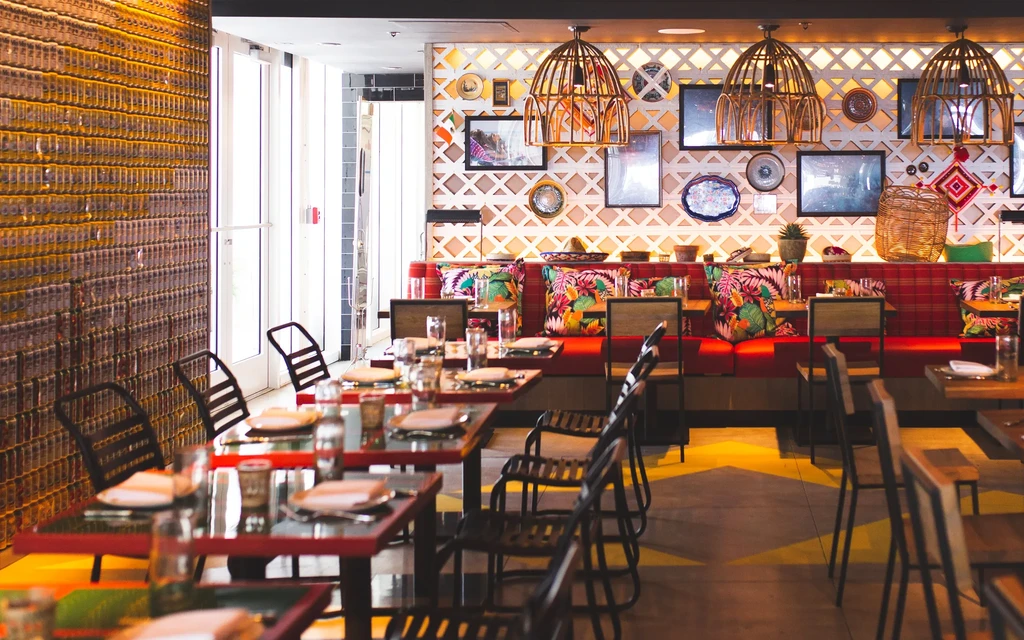 Vibrant restaurant interior featuring red banquettes, golden wall, and eclectic decor.