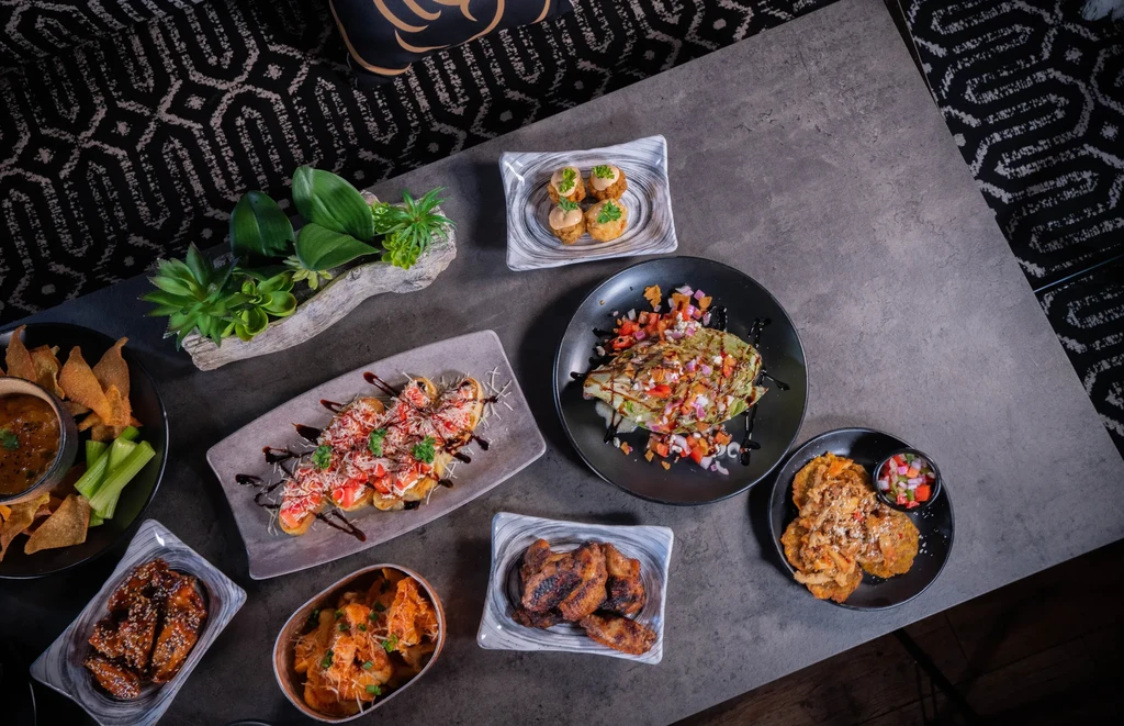 Overhead: assorted appetizers, including bruschetta and chicken wings, on a table.