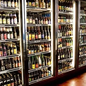 Glass-front commercial refrigerators packed with neatly arranged beer bottles.