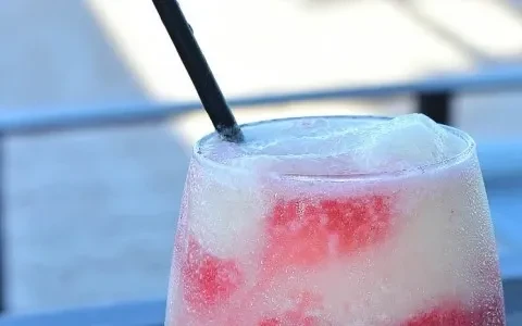 Frozen pink and white drink in a glass with a straw.