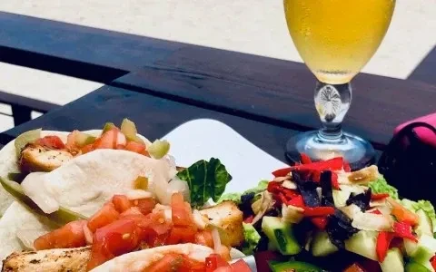 Grilled chicken tacos, salad, and a drink on an outdoor table.