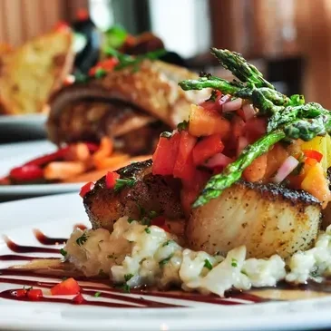 Seared scallops on creamy risotto with tomato salsa and asparagus.