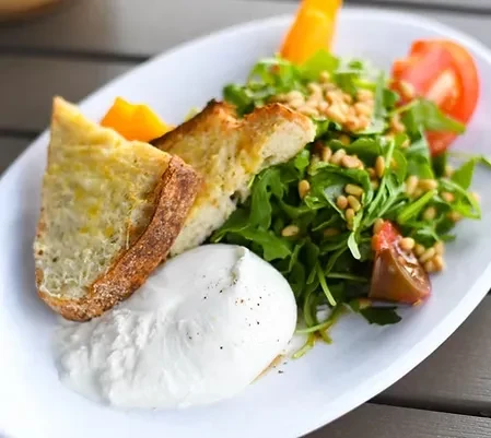 Toasted bread, creamy cheese, arugula salad with tomatoes and pine nuts.