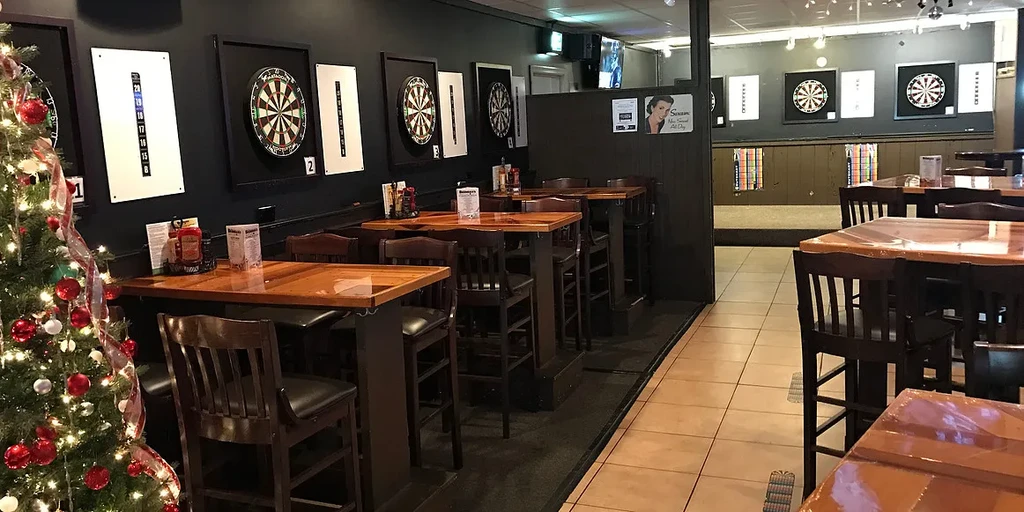 Casual bar interior with high-top tables, dart boards, and a Christmas tree.