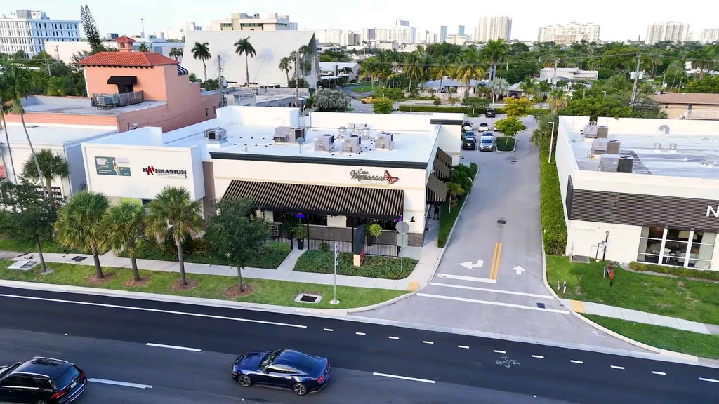 Elevated view of Casa Monarca restaurant on a palm-lined commercial street.