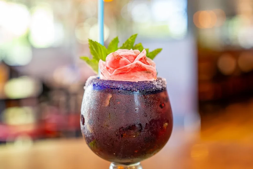Close-up: Frosted purple frozen drink, garnished with rose and mint.