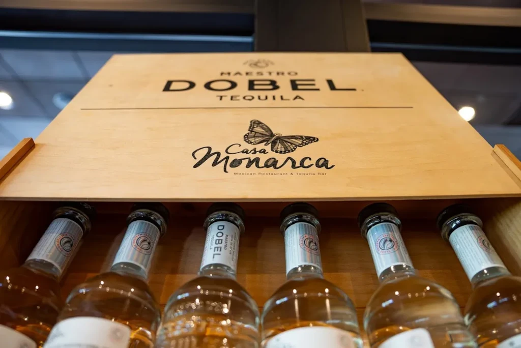 Close-up of Maestro DOBEL tequila bottles in an open wooden box.
