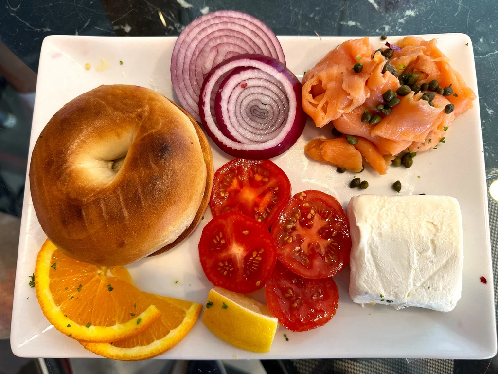Deconstructed bagel and lox platter with cream cheese, salmon, and vegetables.