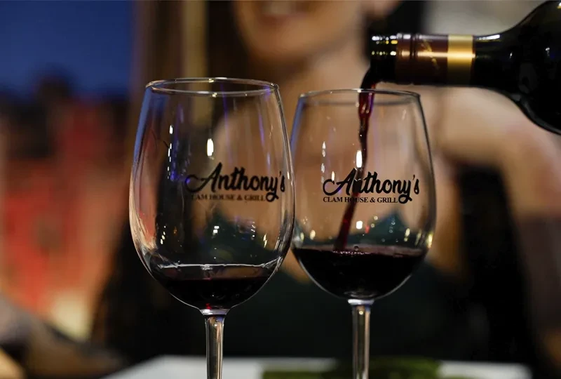 Red wine pours into an Anthony's Clam House & Grill glass.