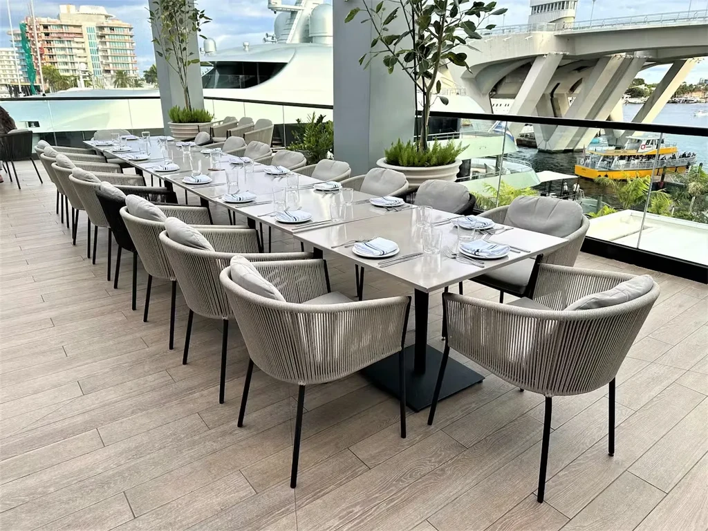 Outdoor dining table on patio overlooking a river, boats, and city.