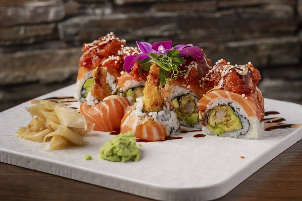 Sushi platter with salmon, tempura shrimp rolls, orchid, ginger, and wasabi.
