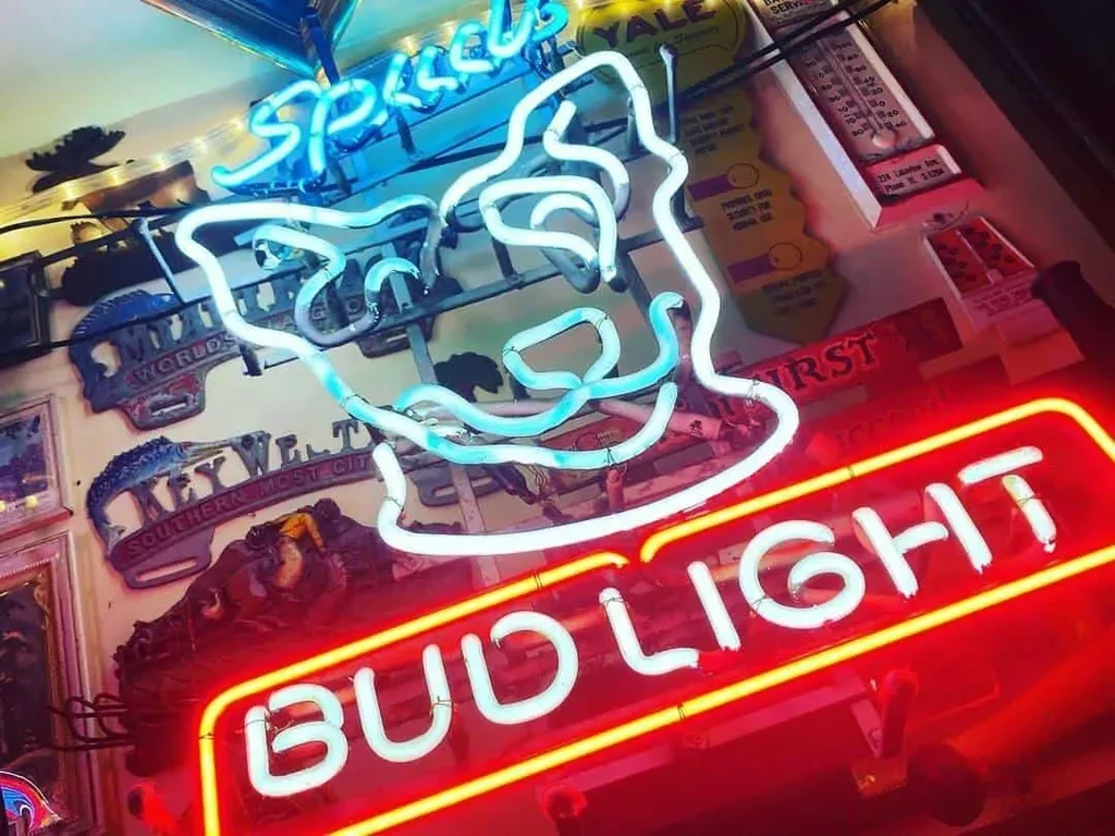 Low-light wall with Bud Light and blue neon signs, vintage decor.