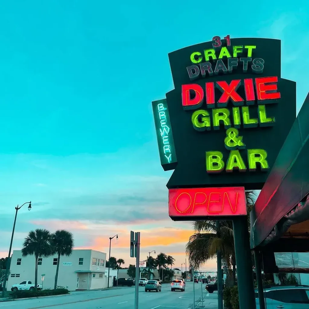 Dixie Grill & Bar neon sign glowing red and green at dusk.
