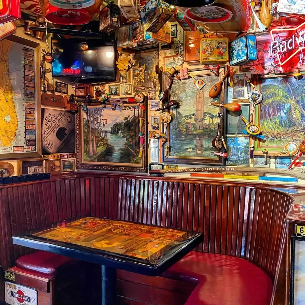 Cozy, maximalist bar interior: red booth, walls densely covered with memorabilia.
