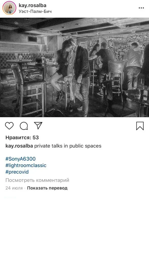Grainy B&W photo: Couple leaning intimately in a dim bar.