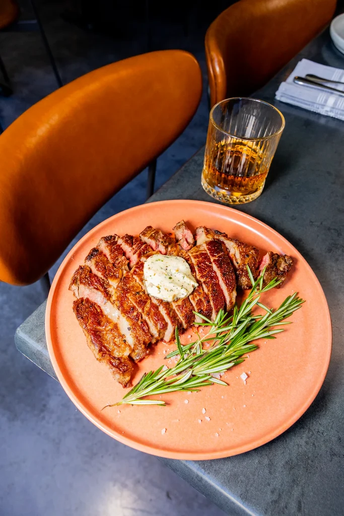 Medium-rare grilled steak with melting herb butter, rosemary, and whiskey.