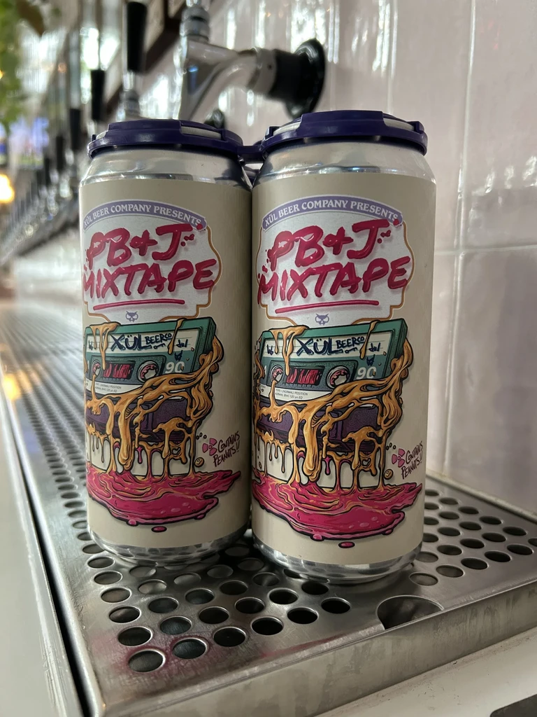 Two XUL PB+J Mixtape beer cans on a bar drip tray.