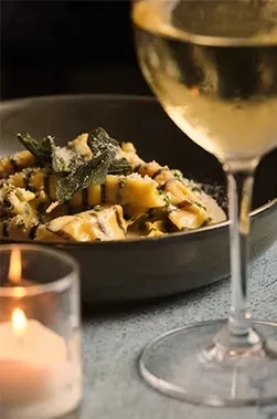 Pasta with creamy sauce, cheese, sage, white wine, and lit candle.