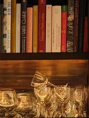 Bookshelf of cookbooks above sparkling clear glass stemware.