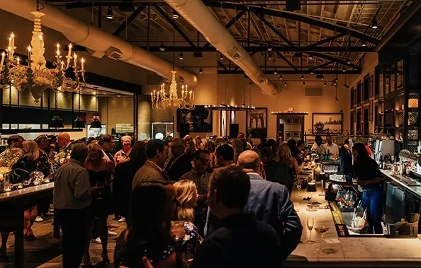 Lively modern bar with dim lighting, elegant chandeliers, and a busy crowd.