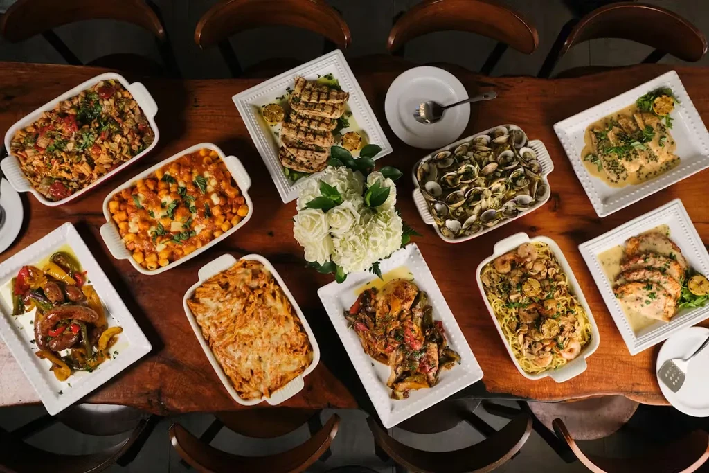 Overhead: Rustic table with nine diverse dishes and a floral centerpiece.