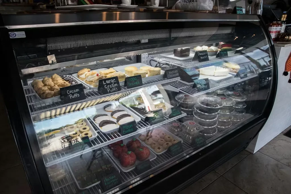 Refrigerated display case with multiple shelves of assorted desserts.