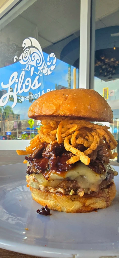 Large burger with pulled meat, cheese, coleslaw, and crispy onion strings.