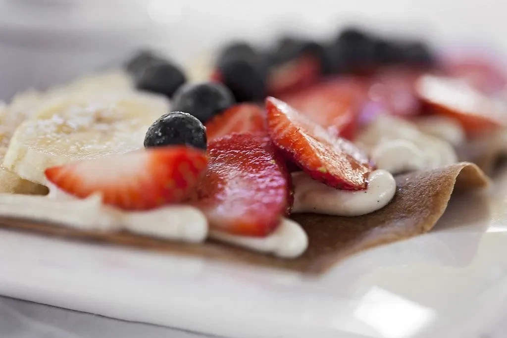 Crepe topped with strawberries, blueberries, banana, and cream.