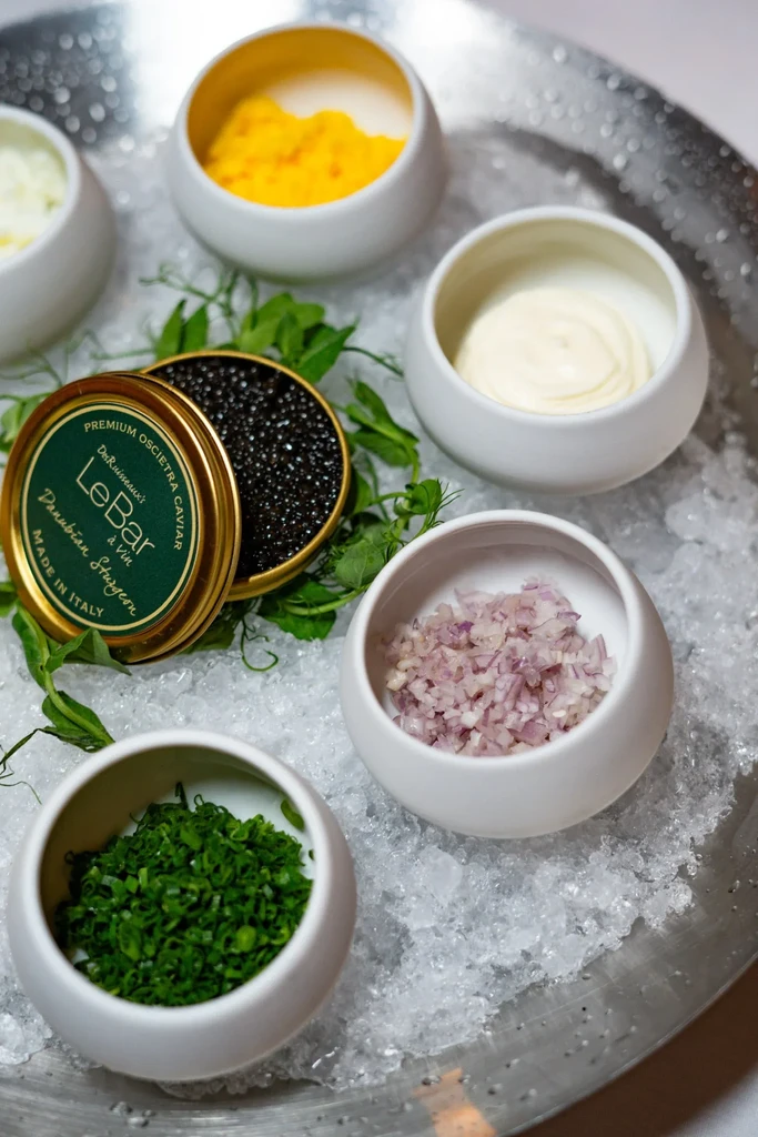 Premium Oscietra caviar tin and five accompaniments on crushed ice.