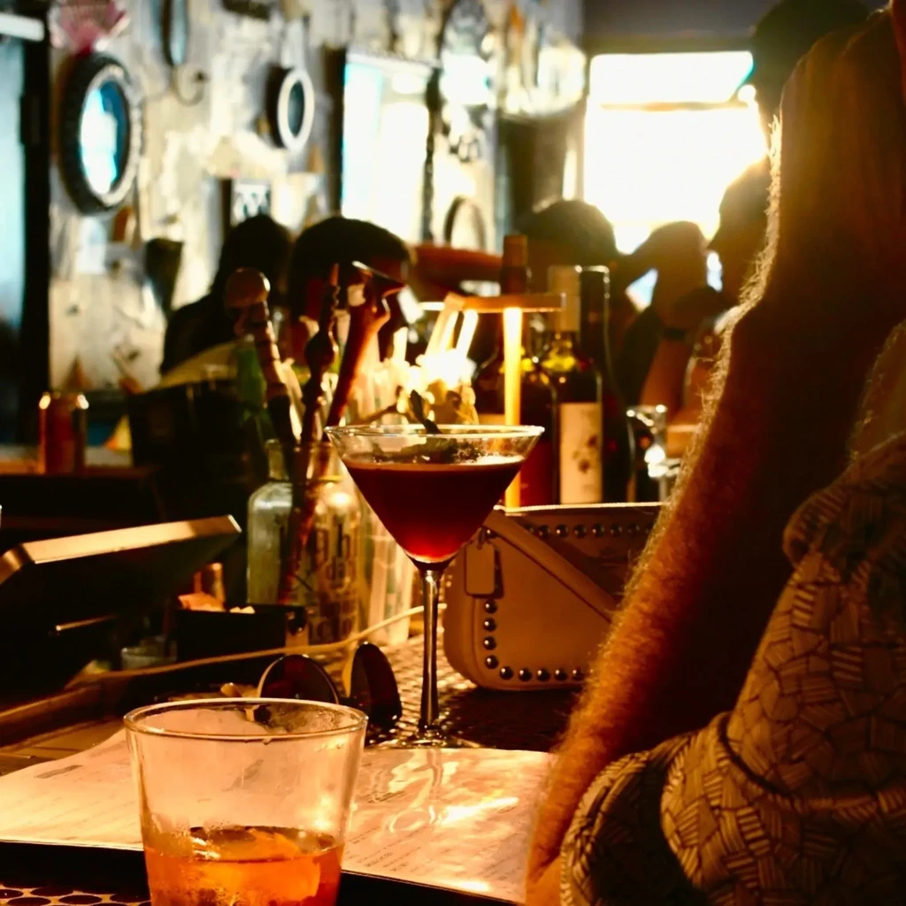 Ruby-red martini cocktail on a cozy bar with blurred patrons.