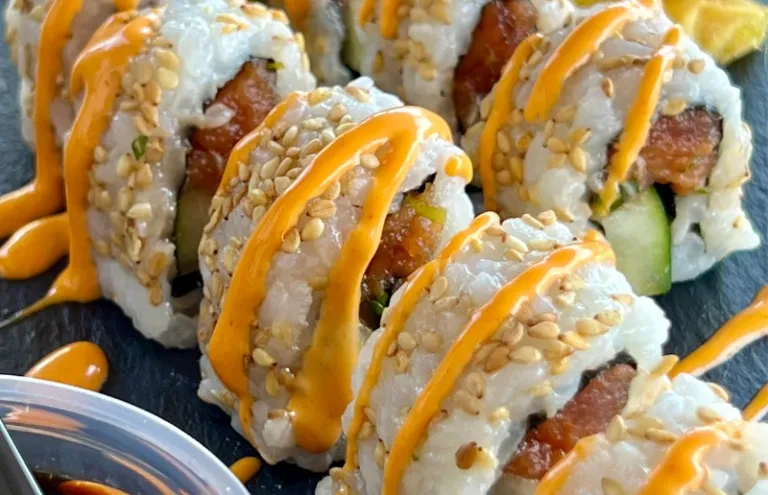 Sushi rolls with fish, cucumber, sesame seeds, and orange sauce.