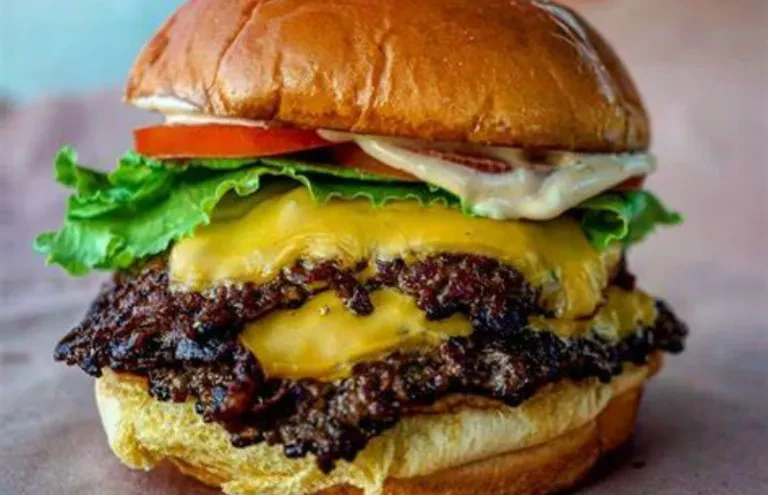 Close-up of a double cheeseburger with melted cheese, lettuce, and tomato.