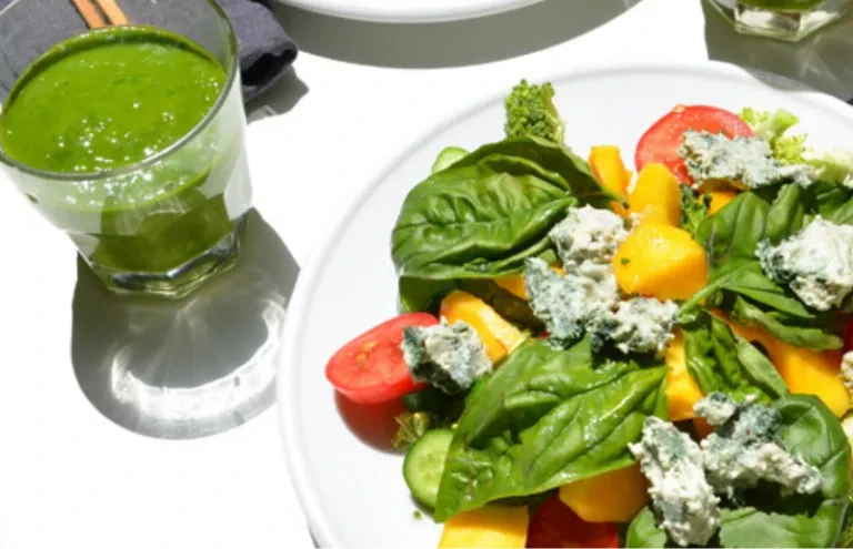 Close-up of a colorful salad with blue cheese and a green smoothie.