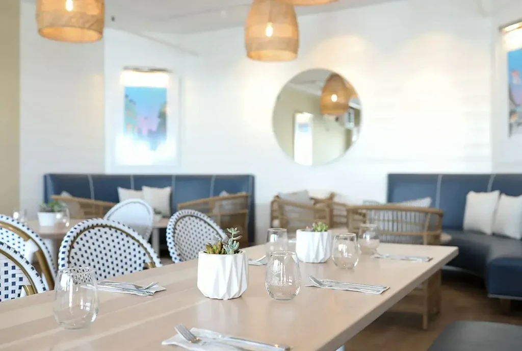 Bright, contemporary restaurant interior with a long table and blue banquette.
